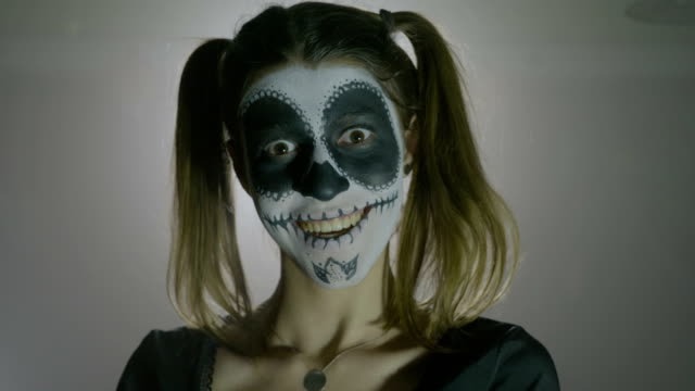 Porträt-von-einem-Halloween-Harley-Quinn-Totenkopf-Horror-Puppe-lachende-Frau-verrückt-auf-grauem-Hintergrund