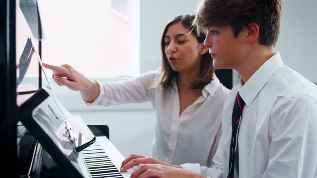 Männliche-Schüler-mit-Lehrer-im-Musikunterricht-Klavier-zu-spielen