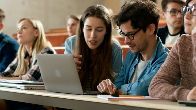 In-der-Klasse-weibliche-und-männliche-Studenten-teilen-und-Laptop,-auf-einem-Vortrag-im-Chat-nutzen.-Junge-Menschen-studieren-und-lernen.-Uni-Leben.