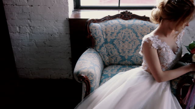 junge-Braut-hält-einen-Blumenstrauß-in-einem-Sessel-sitzend