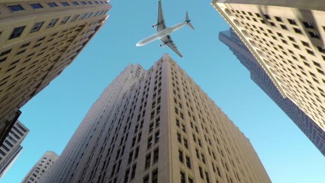 BOTTOM-UP:-Large-commercial-airplane-flies-low-and-close-to-tall-skyscrapers.