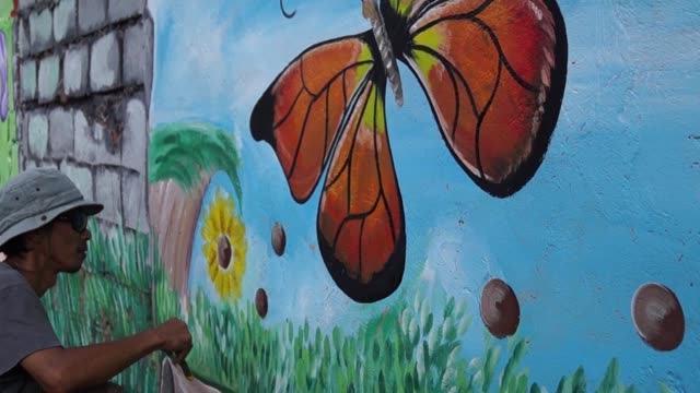 Mural-painter-paints-butterfly-in-color-on-school-wall.-time-lapse