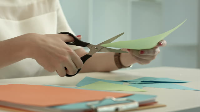 Woman-is-cutting-green-paper-using-scissors