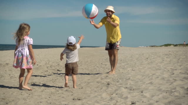 Father-enjoying-playing-ball-with-young-little-kid-on-beach.-Family-Summer-Beach-Vacation.-Slow-Motion.-Children-play-with-dad-on-the-beach.