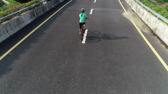 Aerial-view-of-experienced-woman-hands-free-cycling-riding-bike-on-highway-road