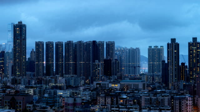 Día-de-lapso-de-tiempo-a-la-noche.-Vista-aérea-de-apartamentos-Hong-Kong-en-el-fondo-del-paisaje-urbano,-Sham-Shui-Po-distrito.-Barrio-residencial-en-la-ciudad-inteligente-en-Asia.