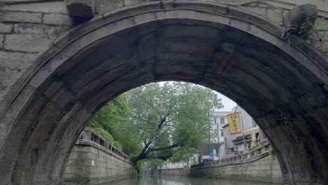 Remo-a-través-del-puente-a-través-de-canales-antiguos-de-ciudad-de-Suzhou-y-casas-populares