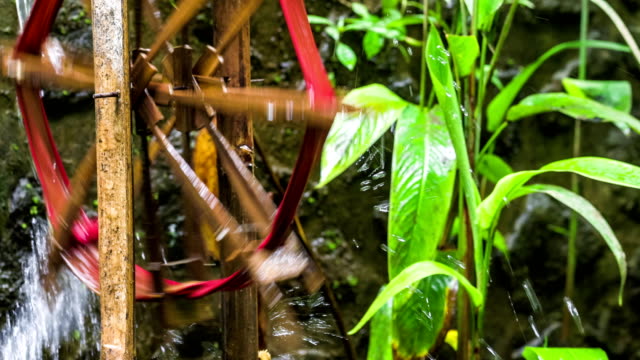 Bamboo-water-wheel-used-for-irrigation,-brings-water-from-stream-to-plantation.-Close-up-of-bamboo-wheel-delivering-water.-Asia