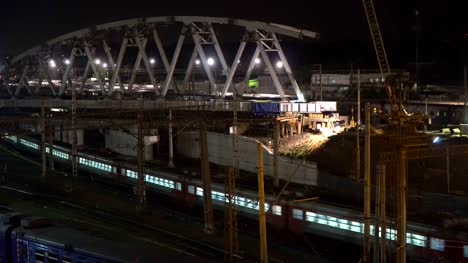 La-construcción-de-un-puente-de-acero-y-movimiento-de-la-noche-de-los-trenes-en-un-cruce-de-ferrocarril