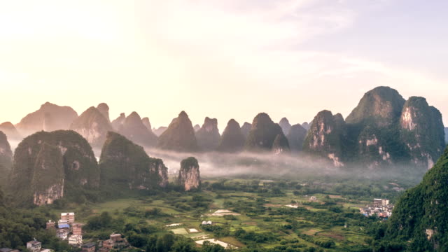 Breathtaking-aerial-establishing-shot-over-beautiful-limestone-karst-mountain-scenery,-covered-with-haze-at-sunset-in,Yangshuo-County,China.Mountain-landscape-top-view