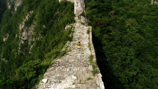 aerial-view-of-young-fitness-woman-trail-runner-running-on-top-of-great-wall