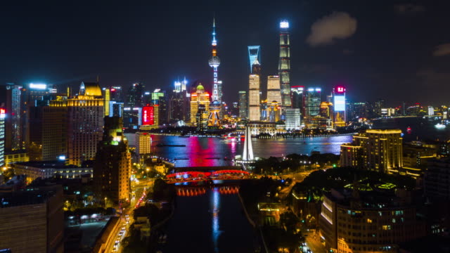 ilumina-la-noche-China-shanghai-panorama-aéreo-del-río-de-la-wusong-paisaje-urbano-pudong-4k-lapso-de-tiempo