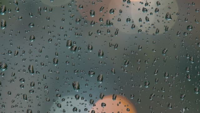 Bokeh-from-street-lights-and-cars-at-rainy-night,-raindrops-on-window.