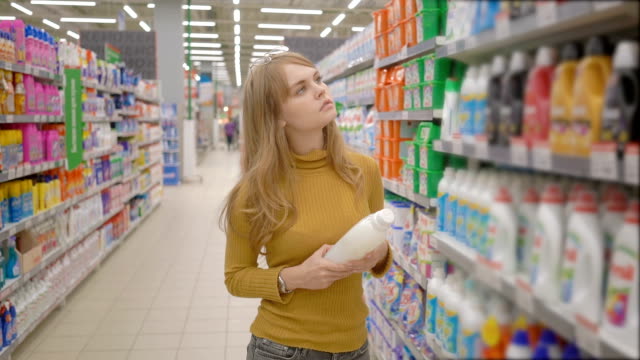 Junge-Frauen-die-Wahl-Haushaltschemikalien-im-Supermarkt.