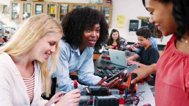 High-School-Teacher-With-Female-Pupils-Building-Robotic-Vehicle-In-Science-Lesson