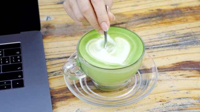 slow-motion-of-hand-stir-a-cup-of-milk-green-tea