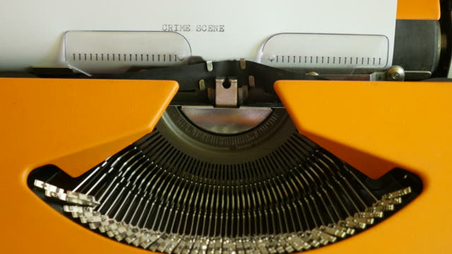 High-angle-shot-of-a-person-writing-CRIME-SCENE-on-an-old-typewriter,-with-sound