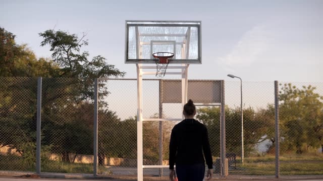 Junge-kaukasischen-weiblichen-Basketball-Spieler-trainieren-und-üben-Kugel-Handhabung-Fähigkeiten-auf-Platz.-Ansicht-der-Rückseite