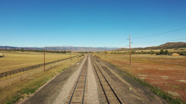 Vista-aérea-a-lo-largo-de-pistas-vacías-del-ferrocarril-hacia-las-estribaciones-de-las-montañas-rocosas-de-Colorado