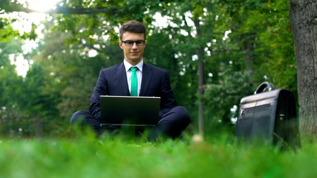 Businessman-sitting-on-grass-in-forest-and-meditating-after-hardworking-day