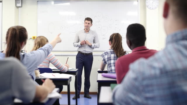 Male-High-School-Tutor-At-Whiteboard-Teaching-Science-Class