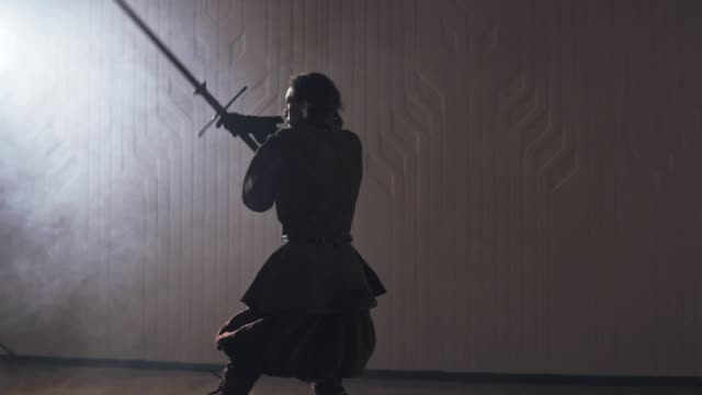 Medieval-warrior-training-with-two-handed-sword-indoors-in-slow-motion