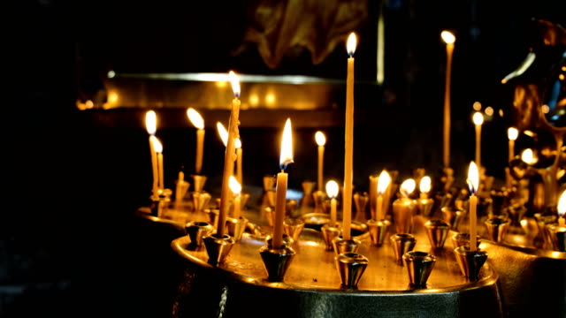 Mujer-enciende-una-vela-de-cera-en-un-incensario-en-un-antiguo-templo-católico-ortodoxo