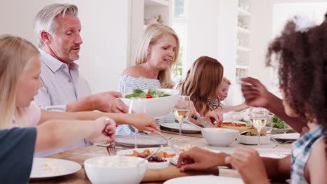 Familia-de-múltiples-generaciones-diciendo-gracia-antes-comida-sentados-a-la-mesa-en-casa