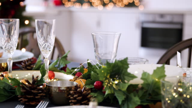 Mediados-de-sección-de-una-mujer-poniendo-una-botella-de-champagne-en-una-mesa-decorada-para-cena-de-Navidad,-enfoque-selectivo
