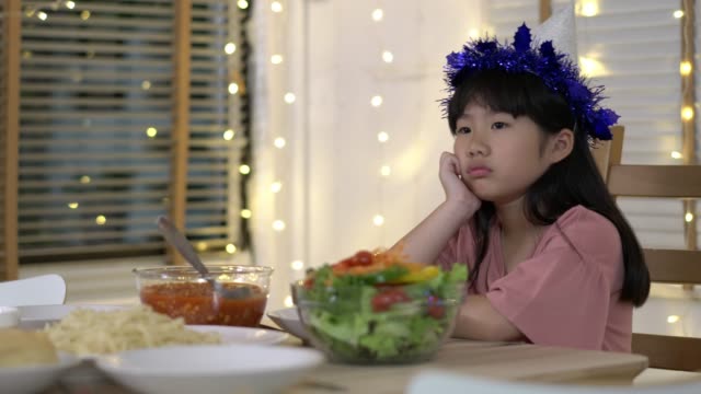 Asian-kids-girl-waiting-father-and-mother-coming-home-birthday-party-and-dinner-together.-Unhappy-family-time-at-home.-Concept-of-lonely,-disappointed-and-sad.