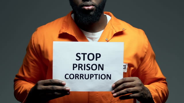 Stop-prison-corruption-phrase-on-cardboard-in-hands-of-black-prisoner,-disorder