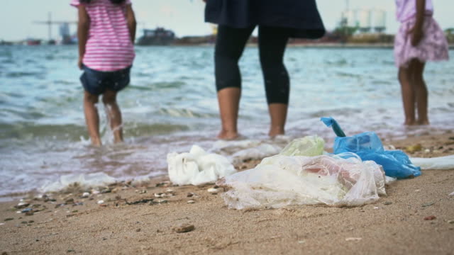 Residuos-plásticos-y-basura-con-mamá-e-hija-jugando-en-la-playa