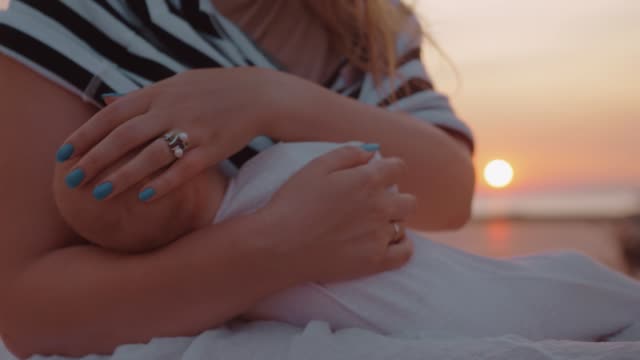 Mother-breastfeeding-baby-outdoor-at-sunset