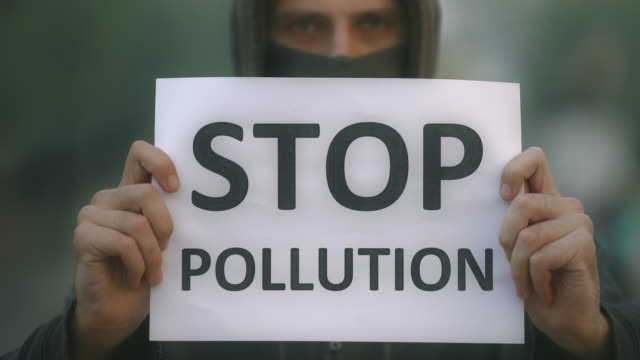 People-in-mask-closeup-look-at-camera-background-road-with-banner-stop-pollution