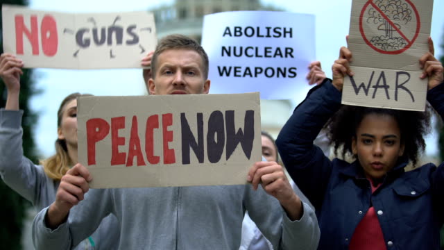 Aktivisten-schwenken-Transparente,-die-gegen-Massenerschießungen,-Atomwaffen,-Krieg-protestieren