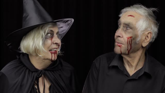 Elderly-man-and-woman-in-Halloween-costumes-making-a-kiss.-Witch-and-zombie