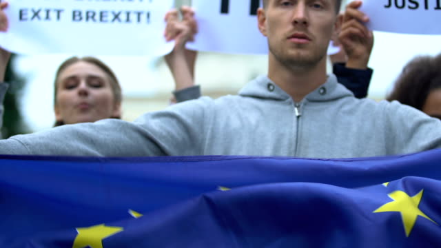 Man-raising-flag-of-European-Union,-protesting-Brexit,-no-borders-for-migration