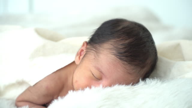 4K-Mittlere-Aufnahme-von-entspannenden-schlafenden-kleinen-asiatischen-Neugeborenen-Baby-Junge-Sohn-liegt-auf-weißem-Bett-mit-Decke-im-Schlafzimmer-zu-Hause.-Süße-unschuldige-Neugeborene-Gesundheit-Pflege-und-empfindliche-Haut-Konzept.