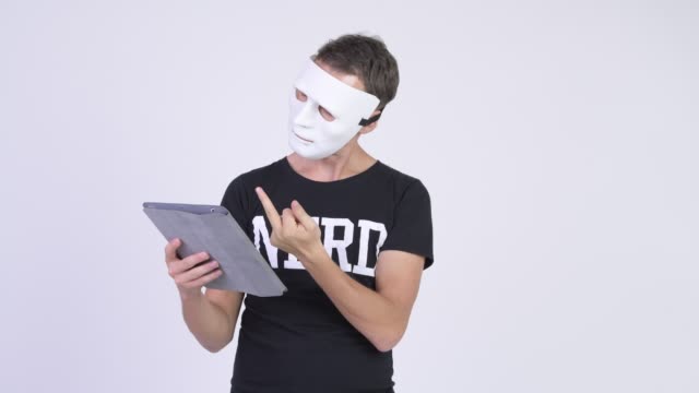 Nerd-Mann-trägt-Maske,-während-digitale-Tablet-als-Hacker