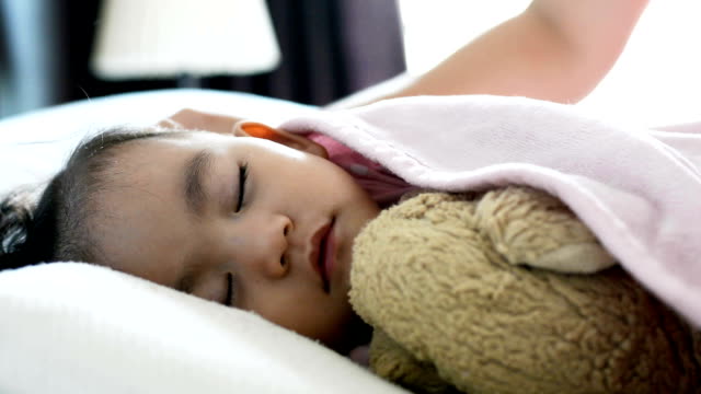 Cerrar-linda-niña-asiática-Durmiendo-en-la-cama,-madre-poniendo-manta-en-un-bebé.-Vista-lateral