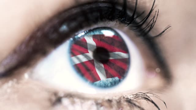 mujer-ojo-azul-en-primer-plano-con-la-bandera-de-Dinamarca-en-el-iris-con-el-movimiento-del-viento.-concepto-de-vídeo