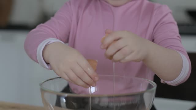 Kleines-Mädchen-bricht-Eier-in-einer-Schüssel-für-die-Herstellung-von-Keksteig