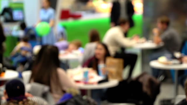 Concept-junk-food.-Unrecognizable-people-eating-fast-food-in-mall-food-court