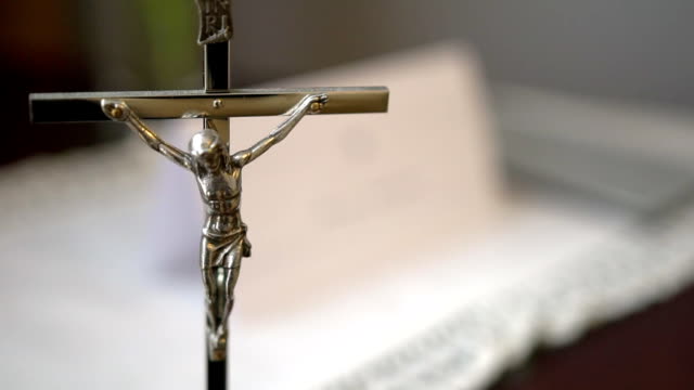 Metal-Crucifix-with-Holy-Bible-Blurred-in-Background