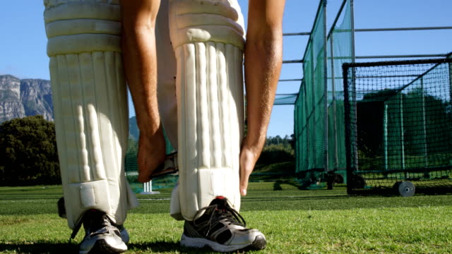 Jugador-de-Cricket-atar-sus-pastillas-de-bateo-durante-una-sesión-de-práctica