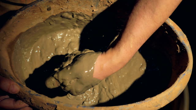 A-close-up-on-a-potters-hand-mixing-wet-clay.
