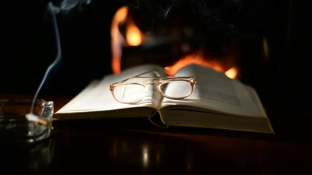 Open-book-on-table-in-front-of-burning-fireplace