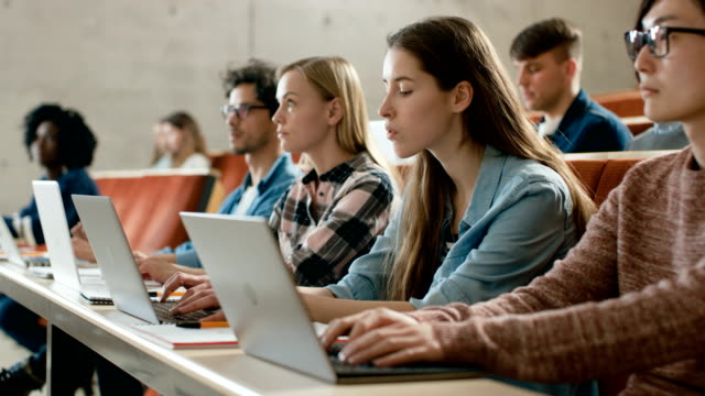 Gran-grupo-de-Multi-étnica-estudiantes-trabajando-en-las-computadoras-portátiles-mientras-se-escucha-a-una-conferencia-en-el-aula-moderna.-Luminoso-estudio-en-la-Universidad-de-los-jóvenes.