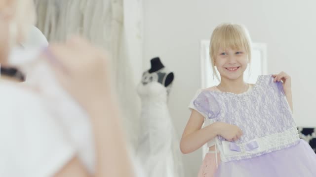 Blonde-Mädchen-6-Jahre-alt-schaut-auf-ihr-neues-elegantes-Kleid.-Eine-Reflexion-im-Spiegel-sieht