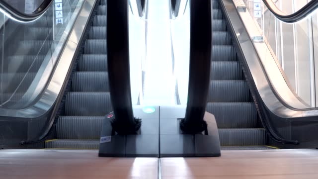 Young-man-walking-down-from-modern-escalator-stairs.-Moving-staircase-running-up-and-down.-urban-lifestyle-concept.